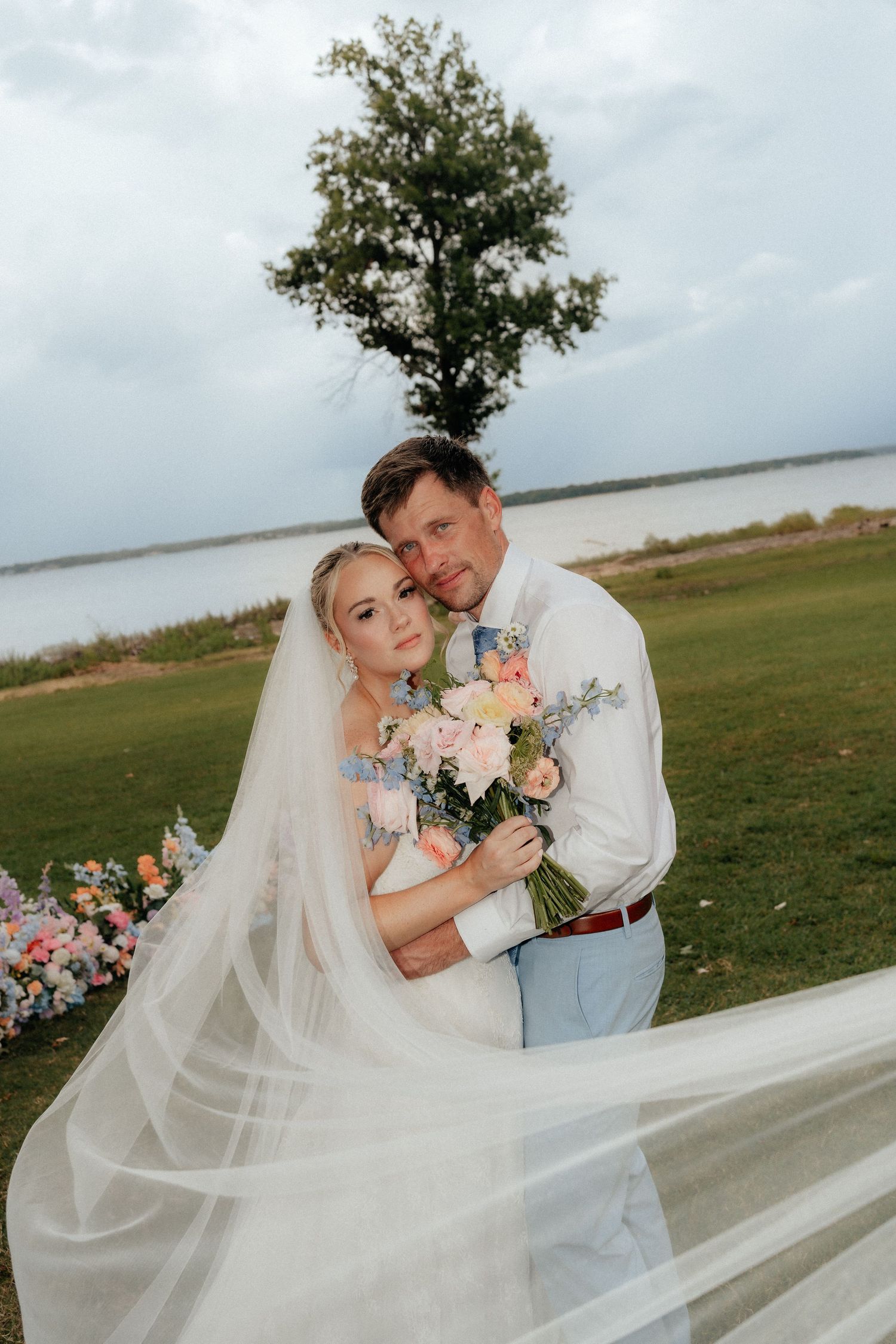 Newlyweds in formal attire pose in front of a modern A-frame church with white spire.
