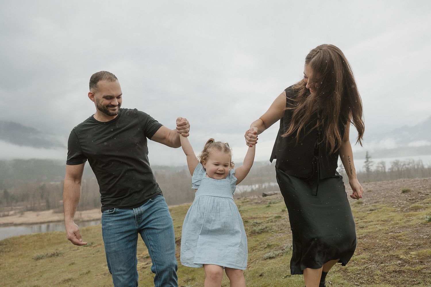 Family holding hands while running through a misty field together.