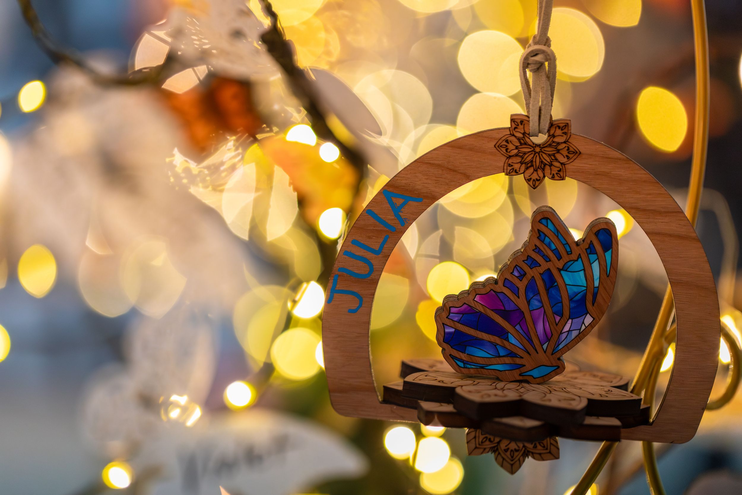 A close-up of colorful monarch butterflies resting on branches with soft glowing bokeh lights in the background.