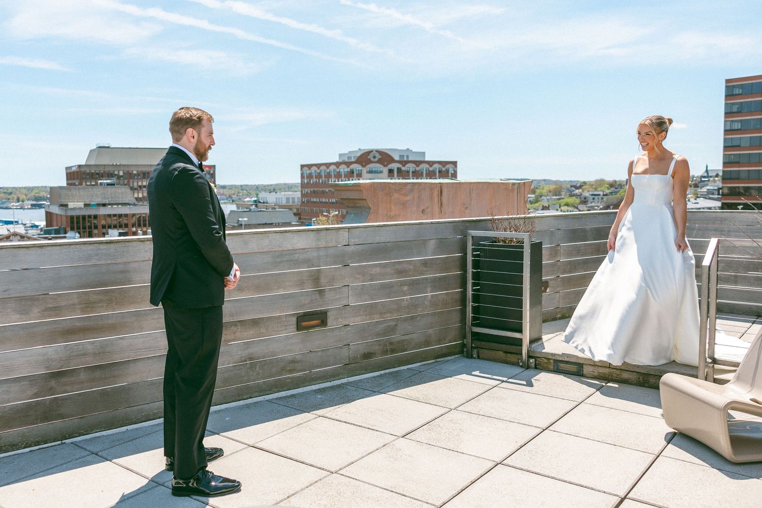 Bride and groom share a first look moment on a rooftop terrace with city views on their wedding day.