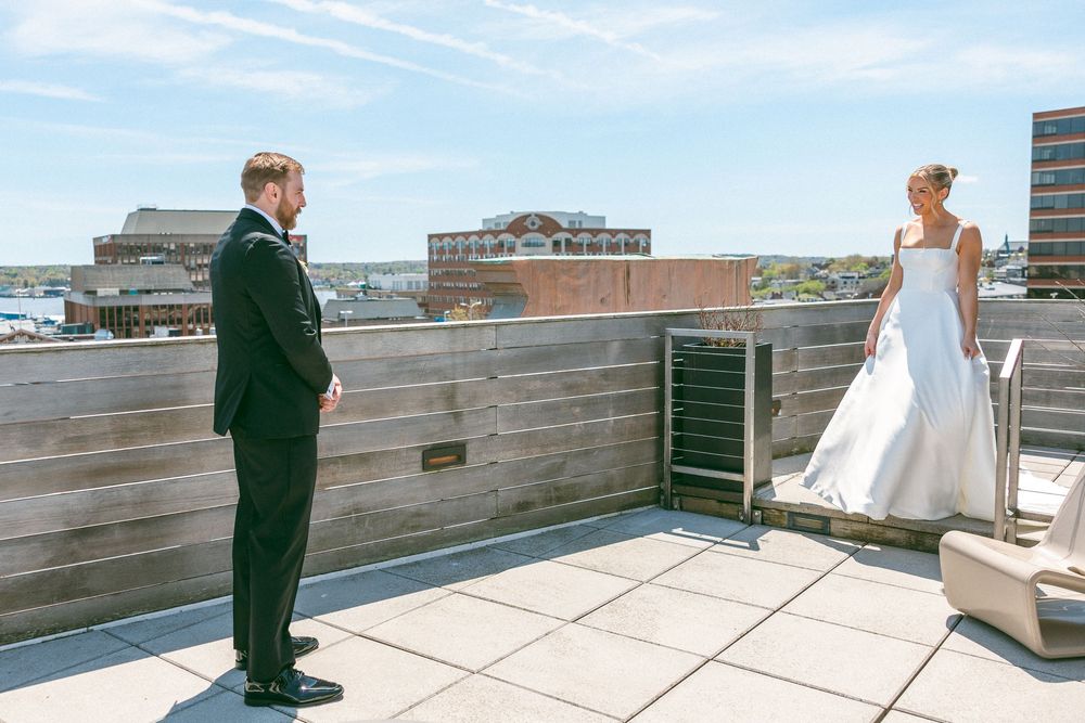 Bride and groom share a first look moment on a rooftop terrace with city views on their wedding day.
