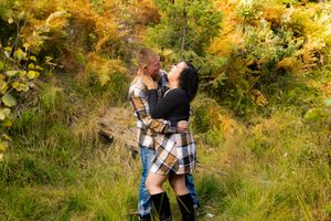Couple embracing in golden autumn foliage during sunset.