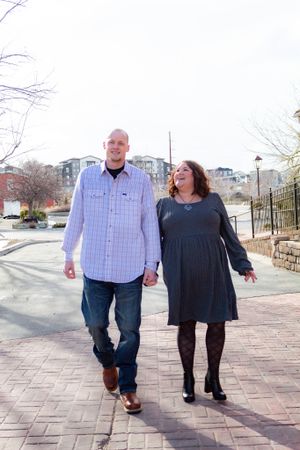 A couple walking and laughing together on a brick pathway during winter.