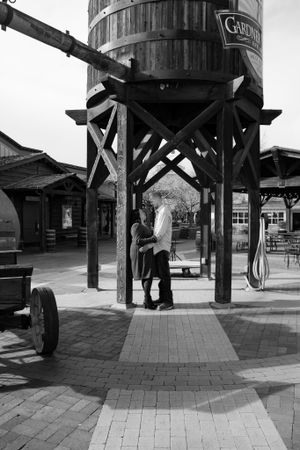 Black and white photos of a couple under a rustic wooden water tower structure.