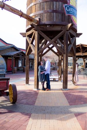 A series of engagement photos taken under a wooden water tower on brick pavement.