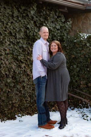 A couple shares loving moments in the snow against a backdrop of winter foliage.