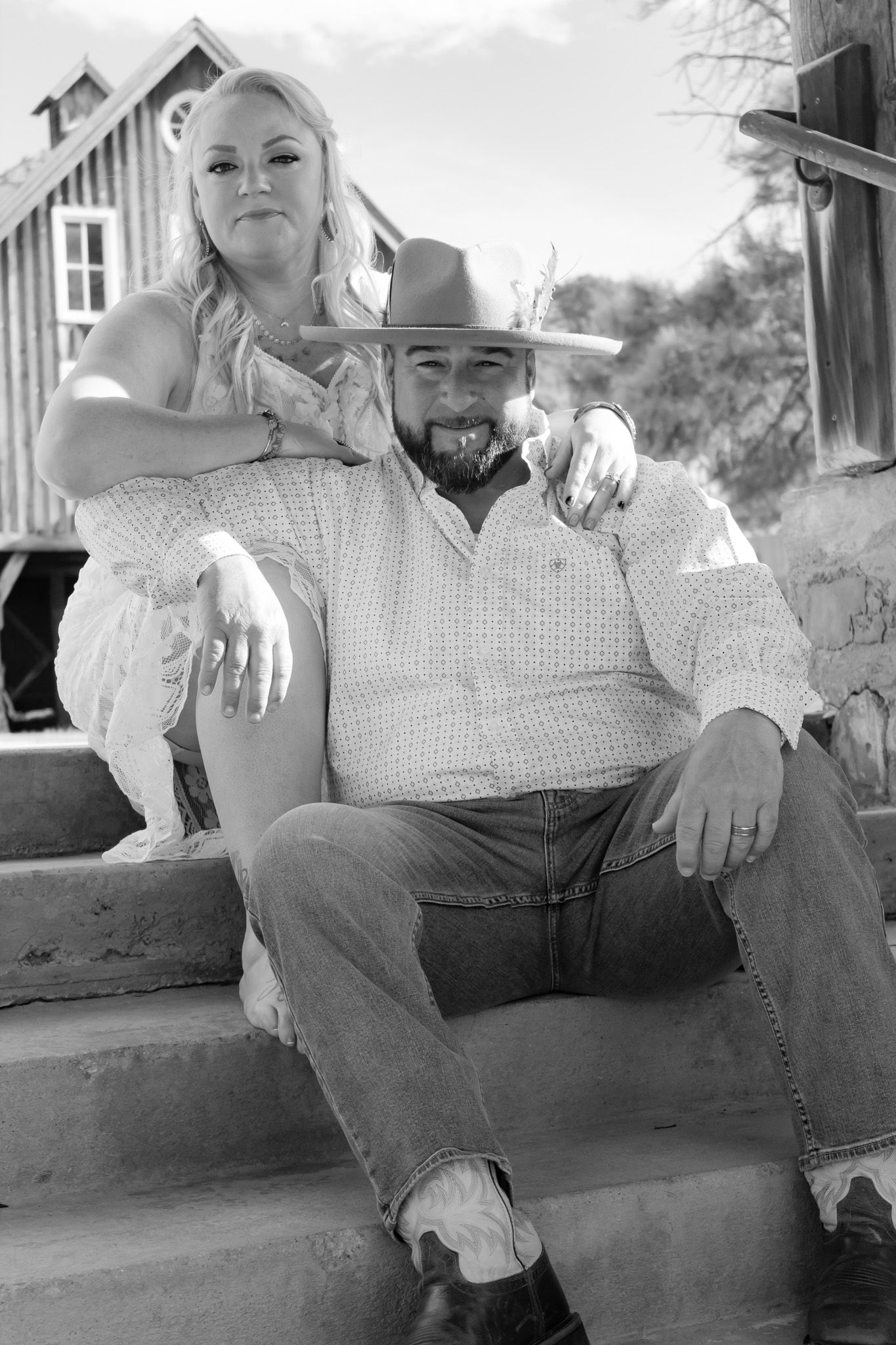 Black and white series of a couple relaxing on outdoor steps in western clothing.