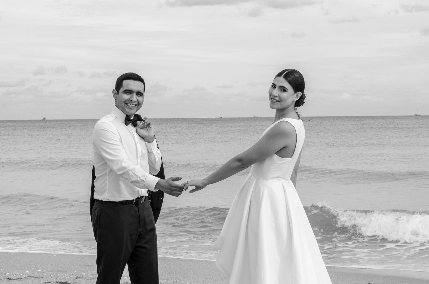 A couple poses playfully on a beach during their wedding photoshoot.