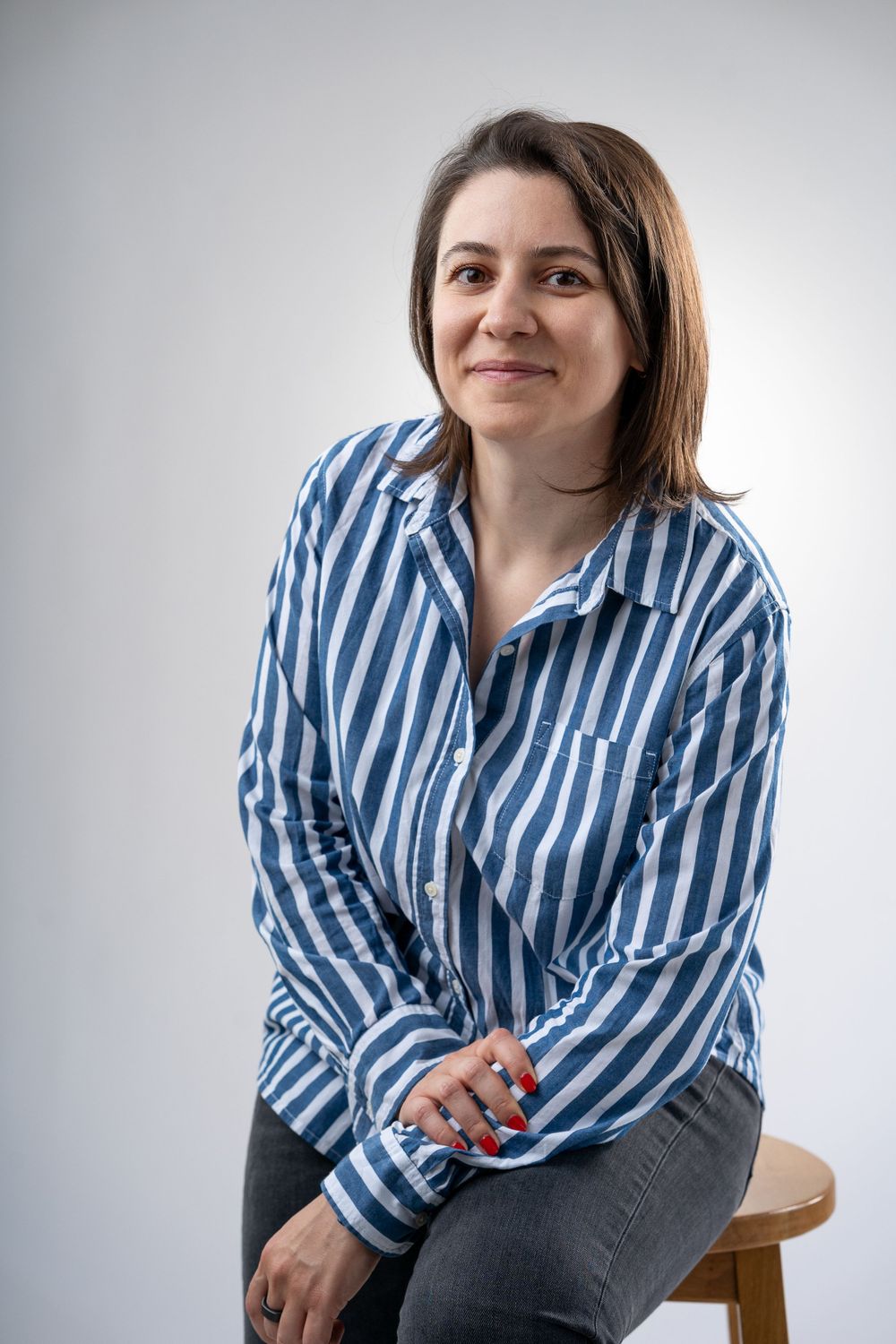 Professional portrait series in blue striped shirt against white background.