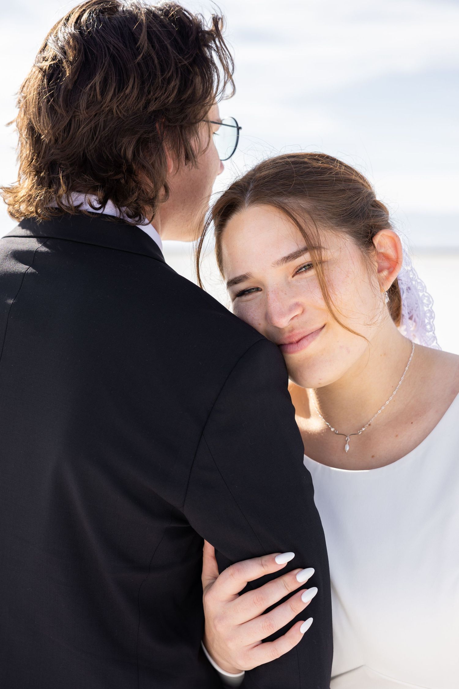 Intimate wedding couple embrace against white background in artistic composition.