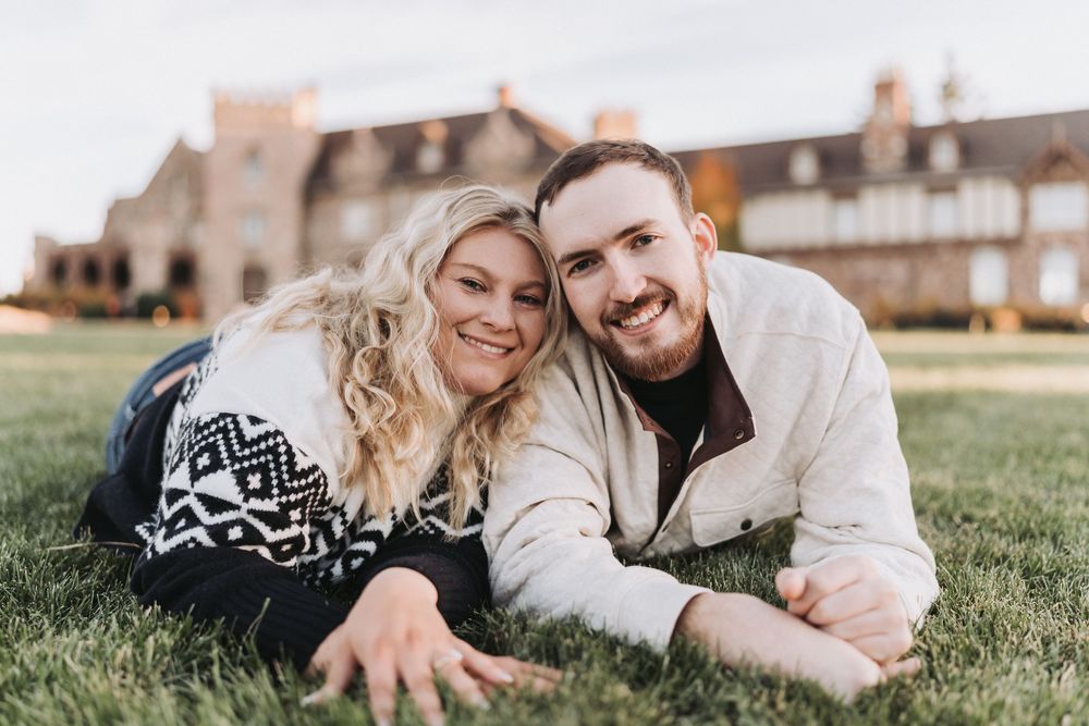 A couple lying together on grass during a sunny outdoor photo session.