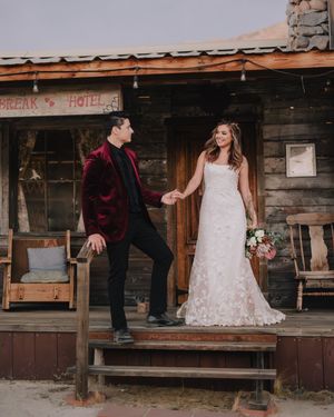 Bride and groom holding hands on rustic wooden porch of vintage hotel during desert wedding.