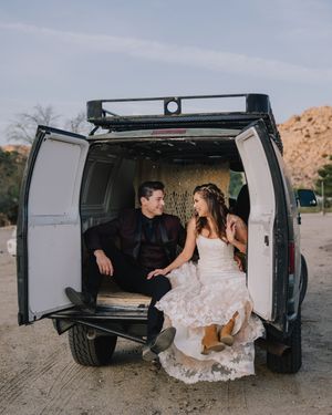 Bride and groom sitting in the back of a white van in the desert, sharing a romantic moment in wedding attire.