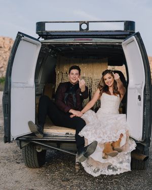 Bride and groom sit laughing in the back of a vintage van at their rustic desert wedding.