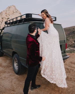 Groom helps bride down from a green vintage van during their adventurous desert elopement.