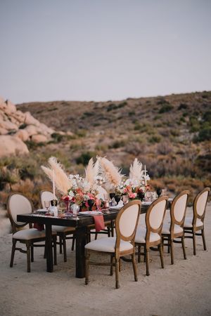 Elegant outdoor desert wedding reception table with pampas grass and floral centerpieces.