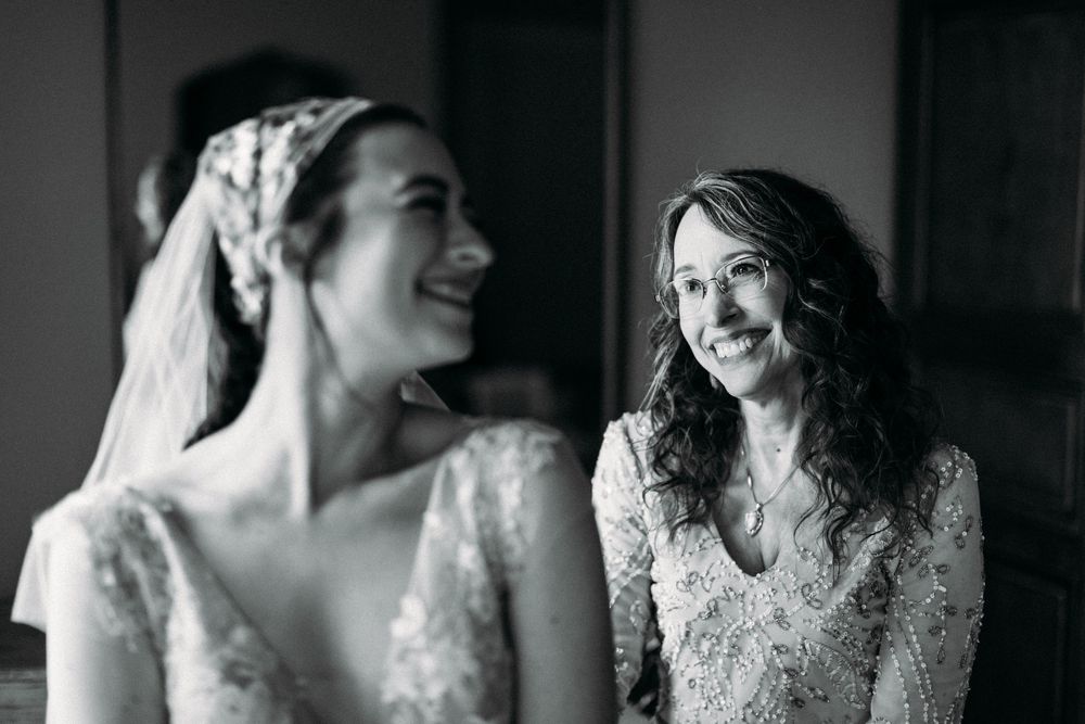 Black and white photo of two people in lace dresses sharing a joyful moment together.