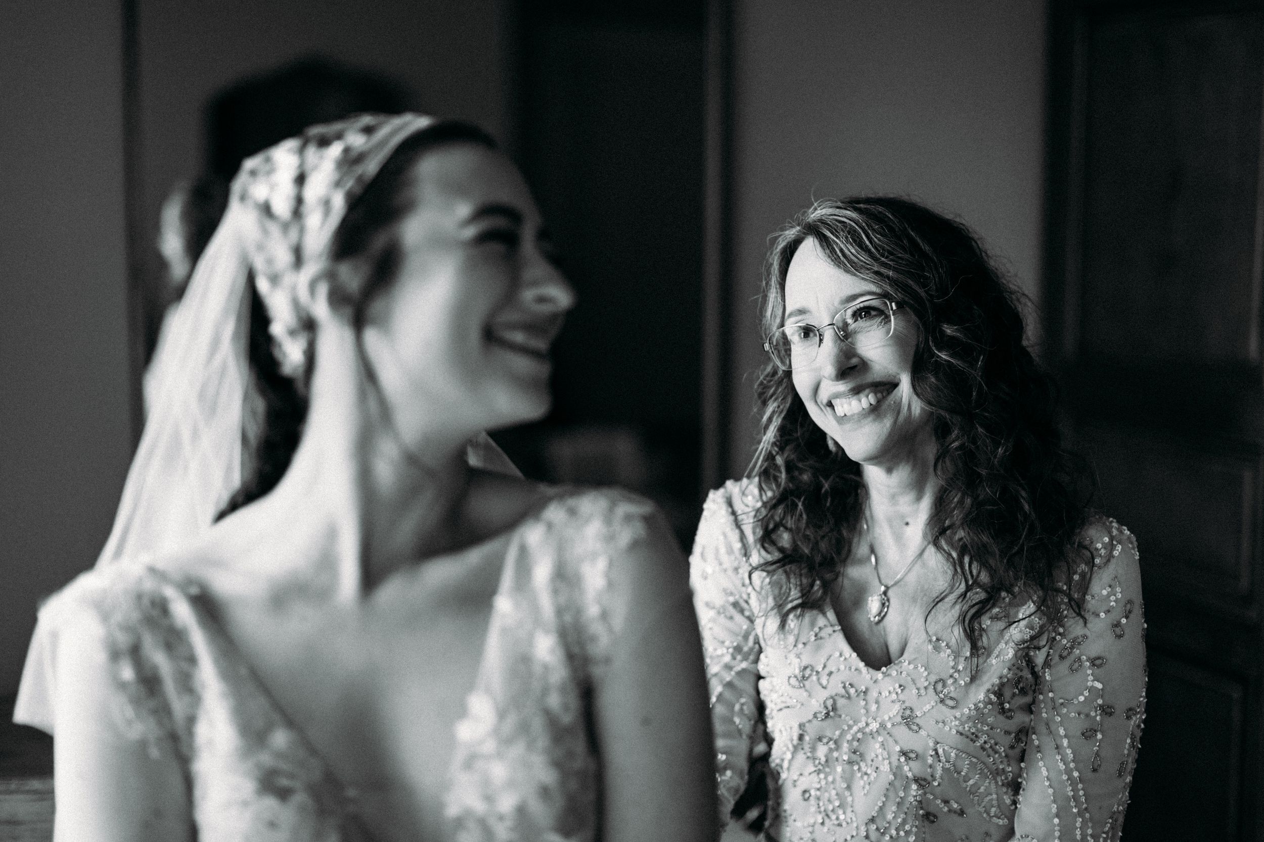 Black and white photo of two people in lace dresses sharing a joyful moment together.