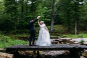 A wedding couple poses together in a lush green forest setting.