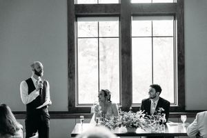 A black and white panoramic wedding reception scene showing silhouettes against large windows.