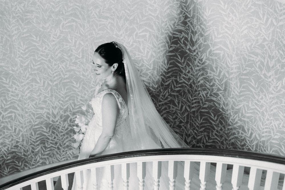 A sequence of black and white wedding photos showing details of a bride's veil and dress against a patterned wallpaper background.