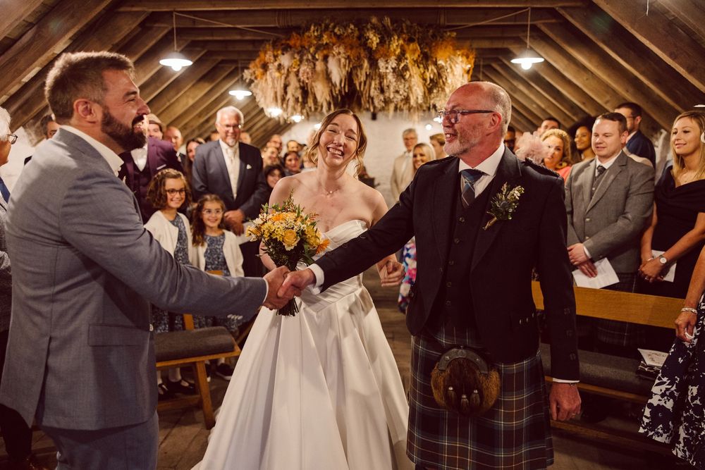 Wedding ceremony guests stand and applaud during a joyous celebration in a rustic wooden venue.
