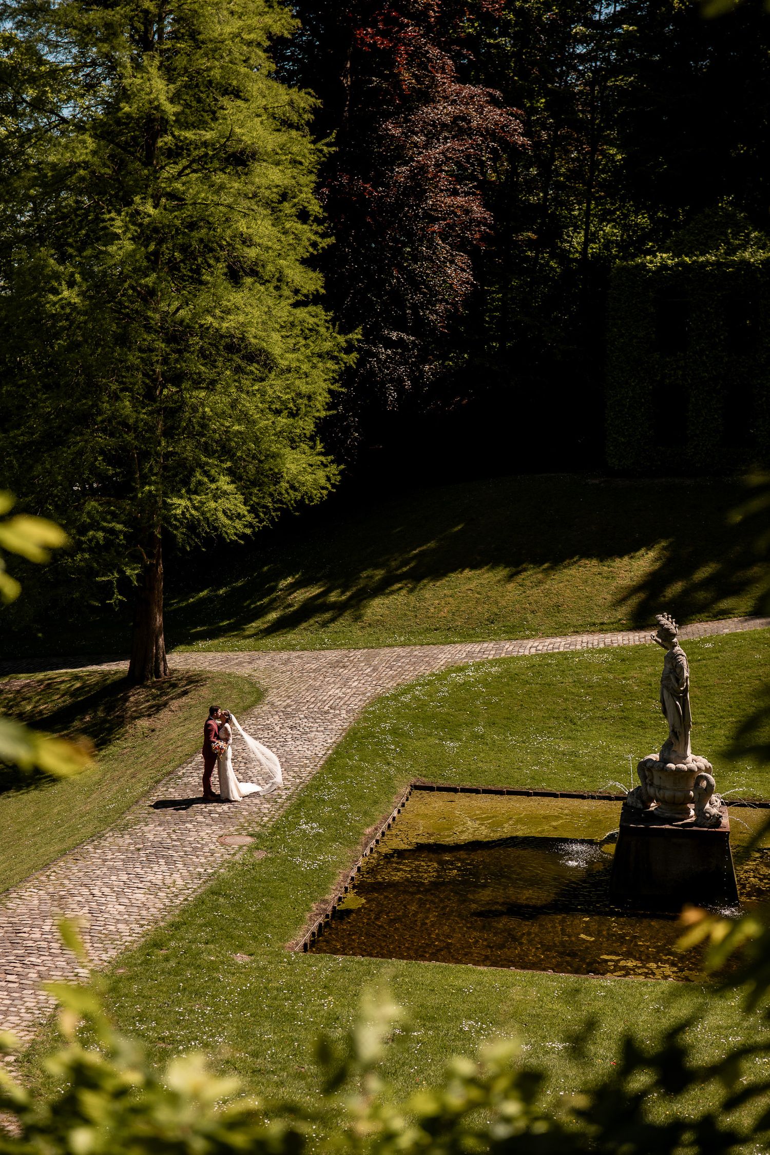 Historische Gartenanlage in Kleve mit Springbrunnen und einer Statue, ein Brautpaar steht auf dem gepflasterten Weg