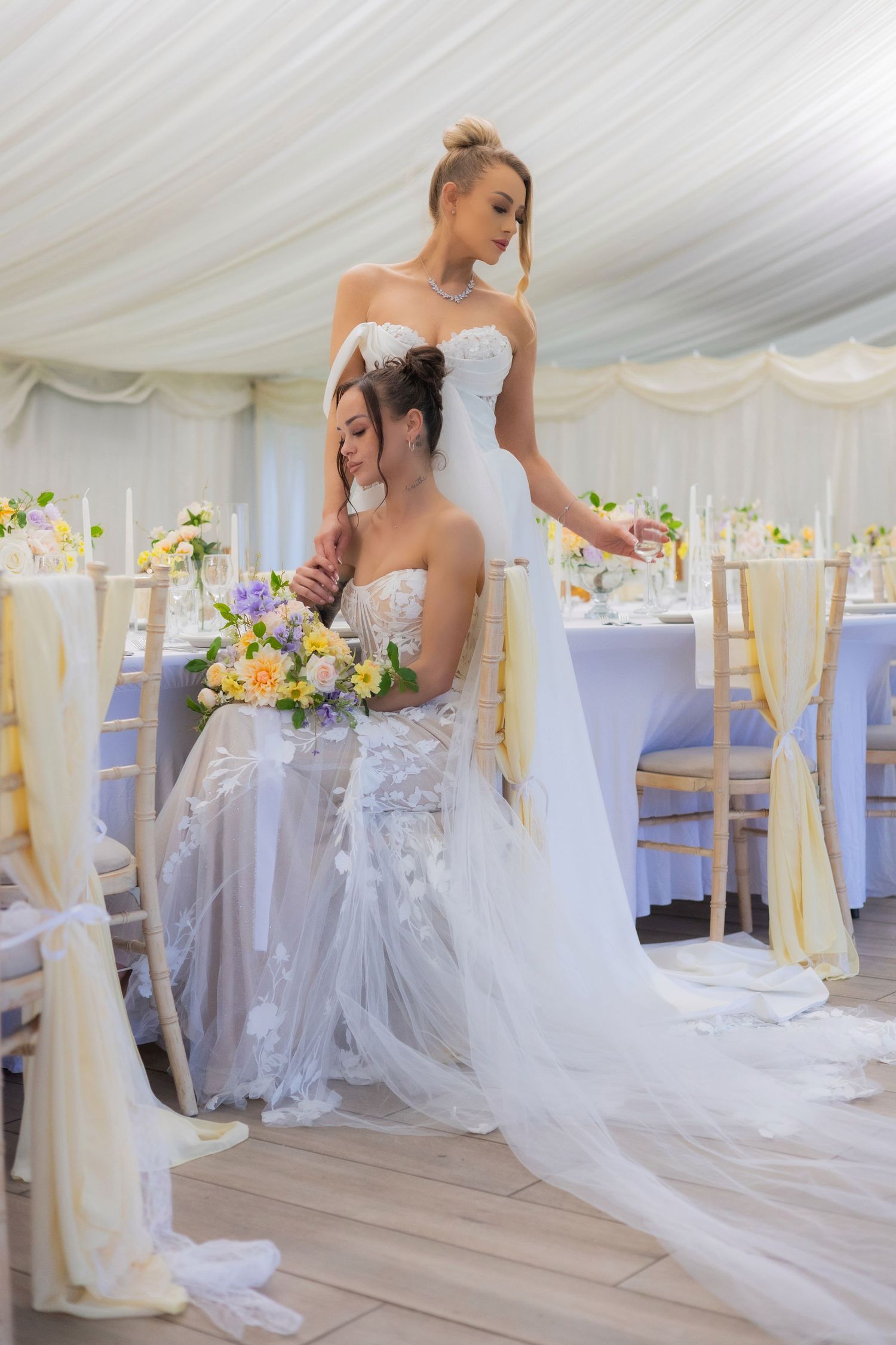 Elegant wedding reception setup with white decor and floral arrangements in marquee tent.