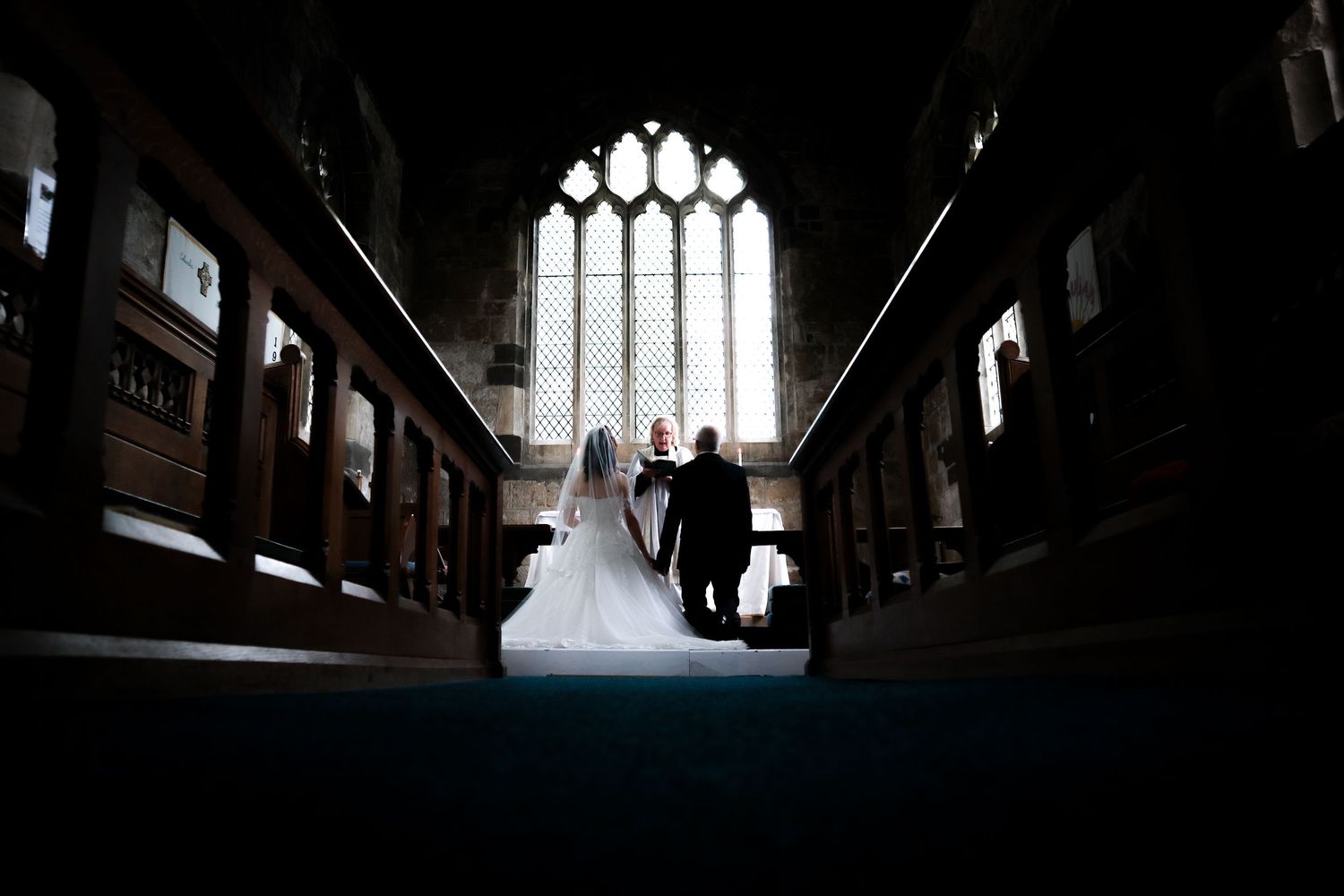 Dark silhouette of a church interior with dramatic stained glass windows.