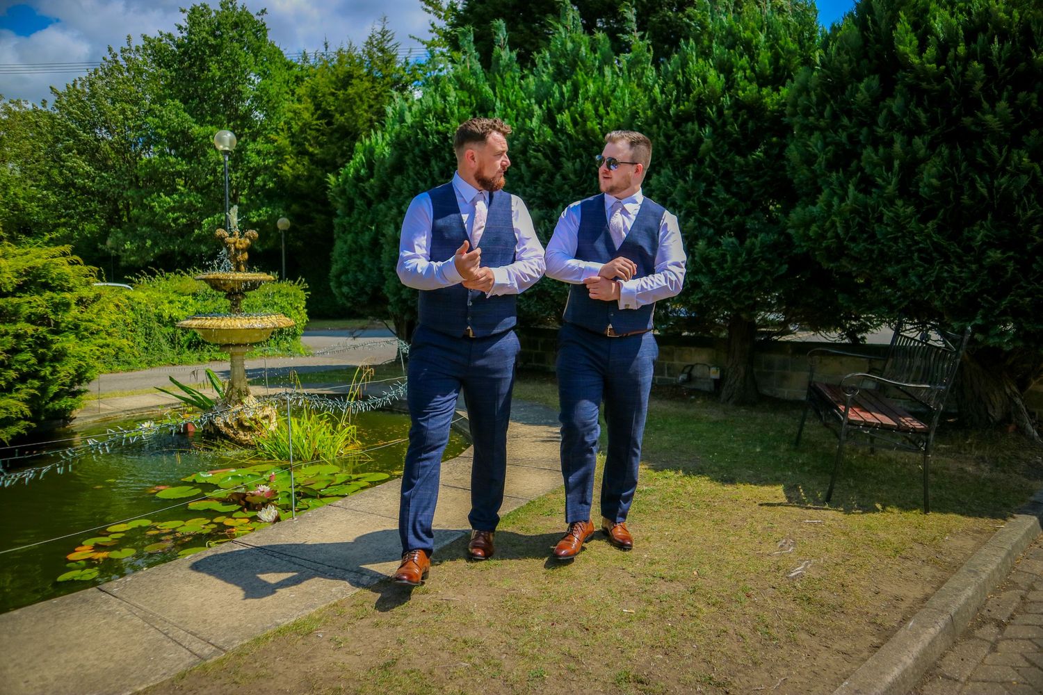 Couple walking together in a lush green garden setting during a wedding photoshoot.