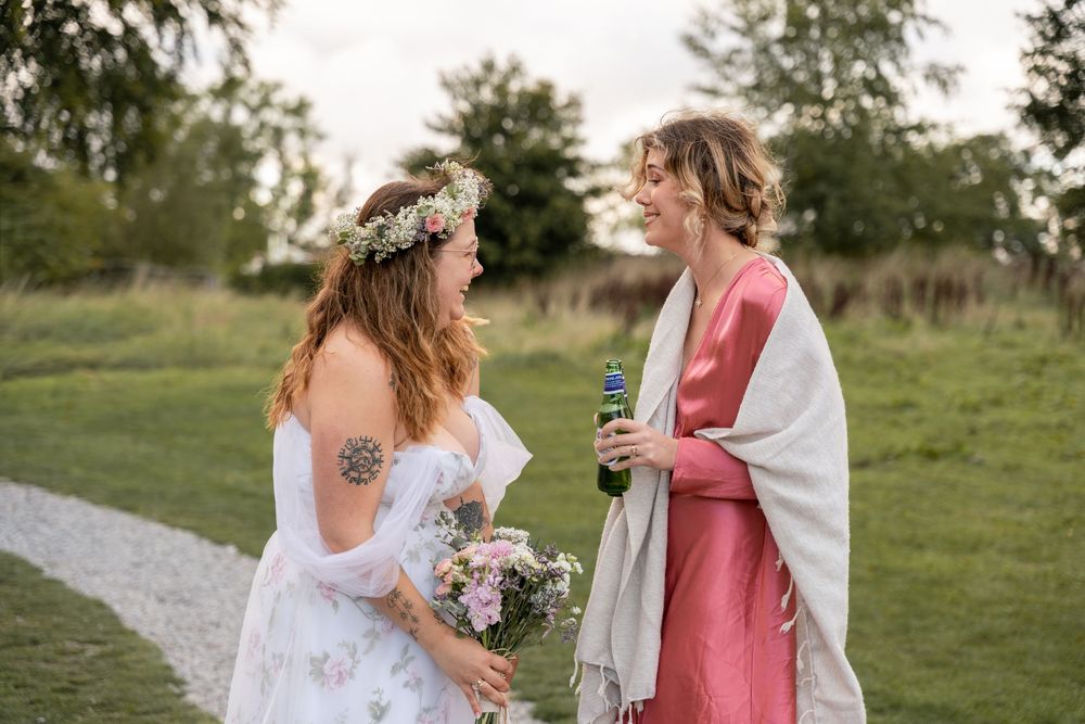 Two people in white and pink attire share a moment outdoors during a summer celebration.