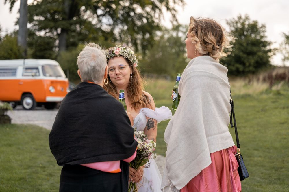 A wedding celebration takes place outdoors on a grassy field with a vintage orange VW bus in the background during a wedding in Lincolnshire