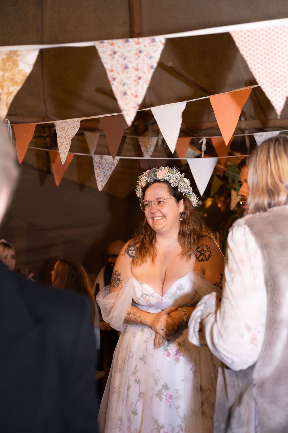 A festive indoor celebration with bunting decorations and people gathered under white and pink triangle flags.
