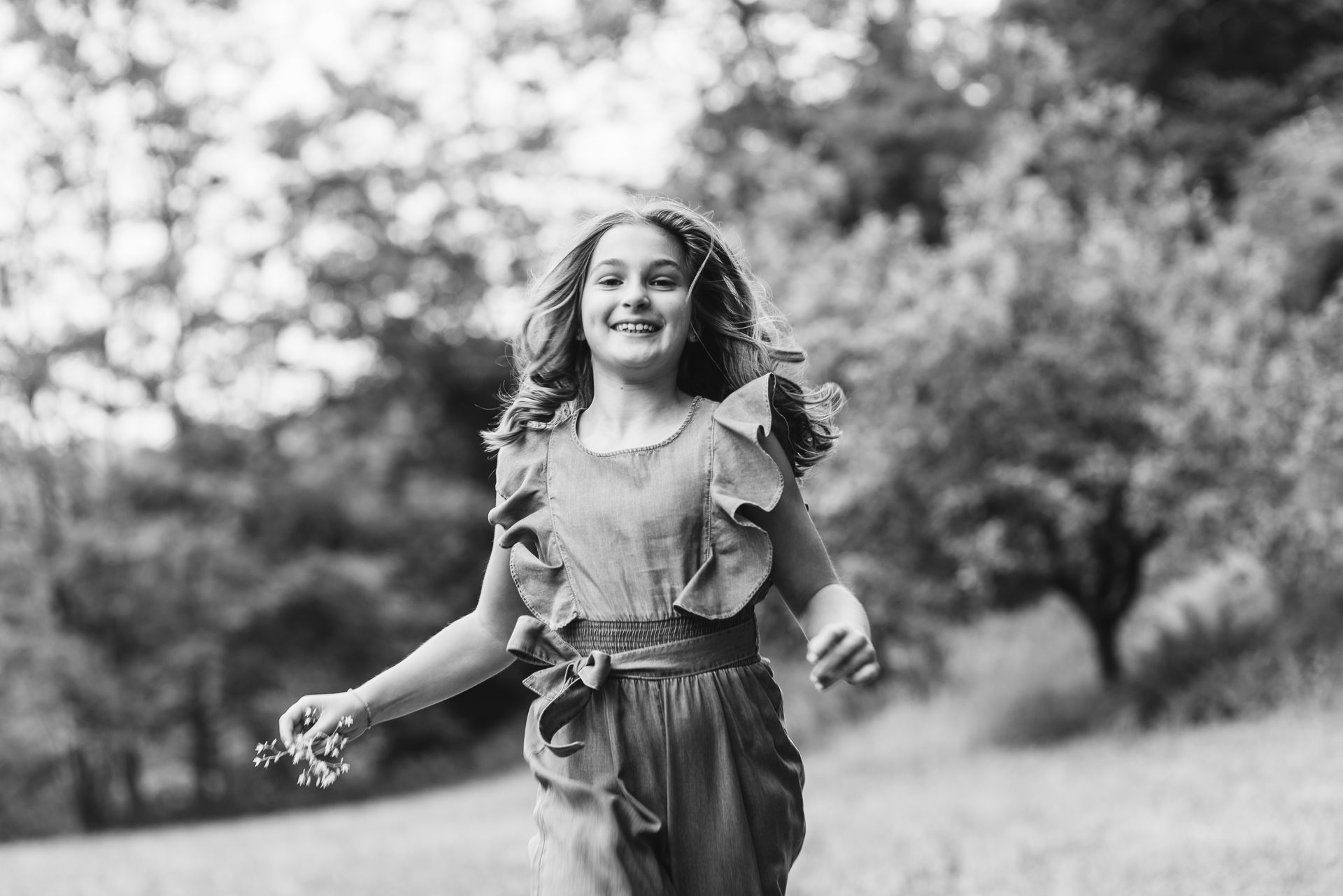 A joyful moment captured in black and white of someone running through a sunny field.