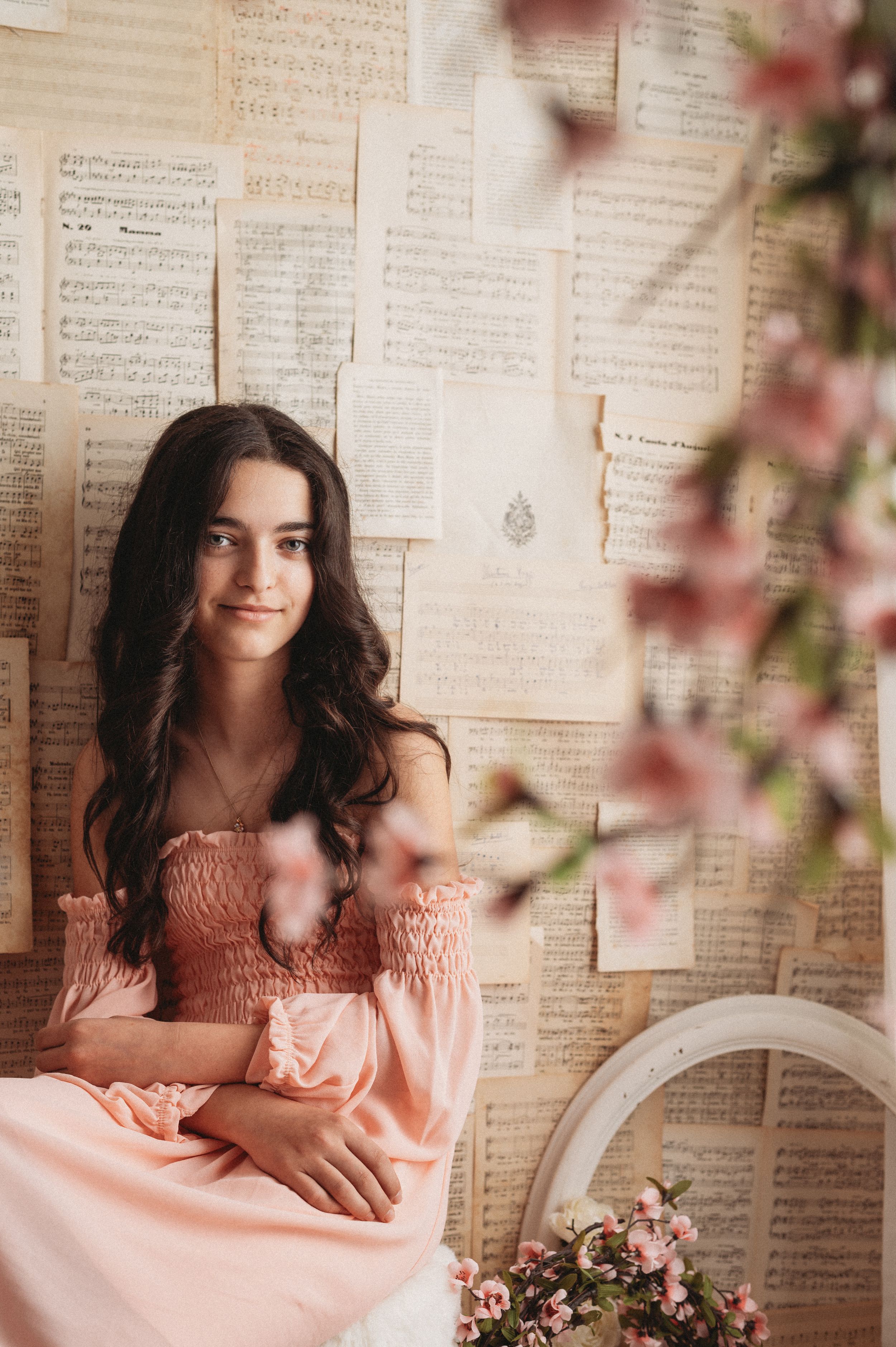 A vintage-inspired portrait with sheet music backdrop, pink dress, and soft floral elements creating a romantic atmosphere.