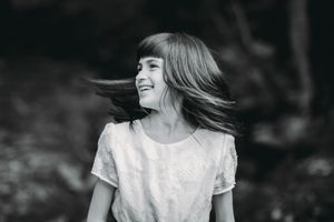 Black and white portrait of person with flowing hair smiling outdoors.