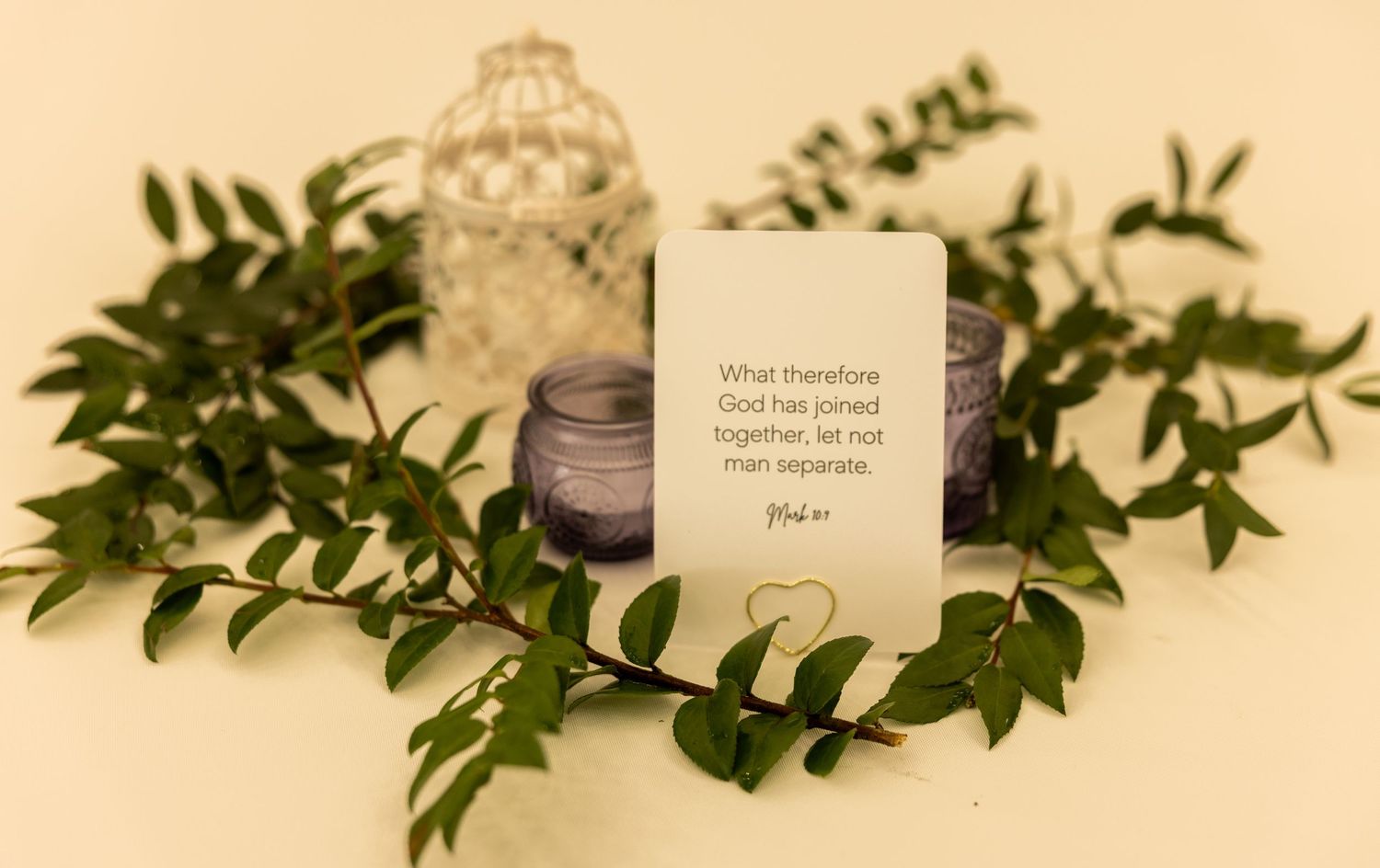 Wedding card with Bible verse Matthew 19:6 surrounded by greenery, purple candle, and lantern.