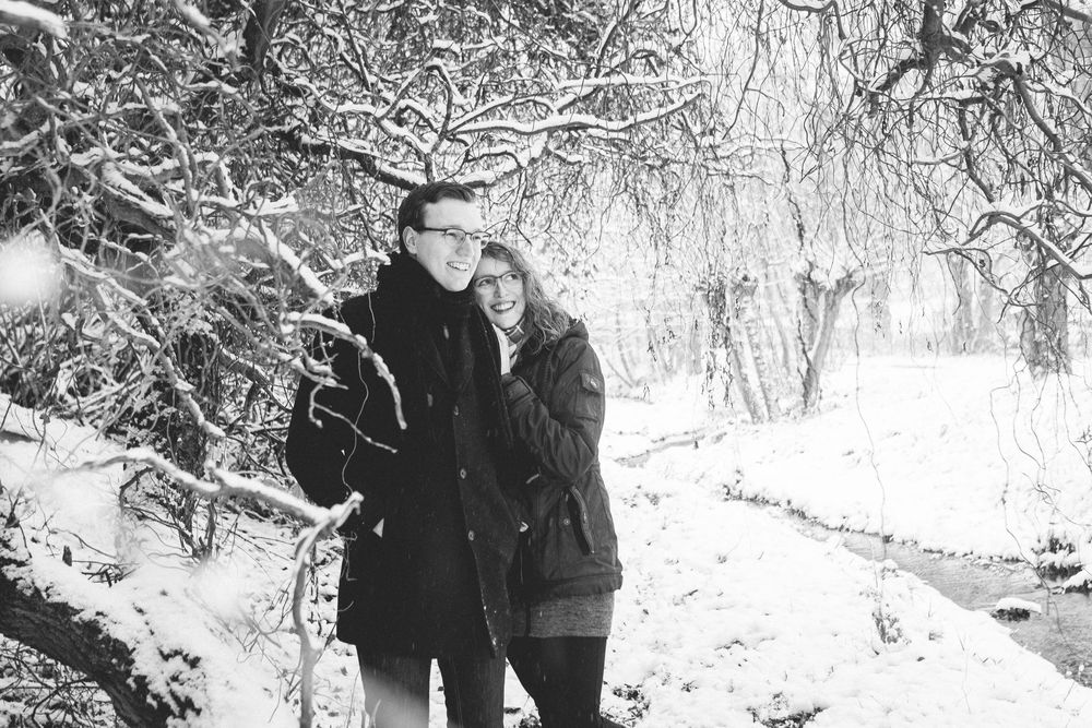 People walking through a snowy forest path during winter with snow-covered tree branches creating a scenic archway.