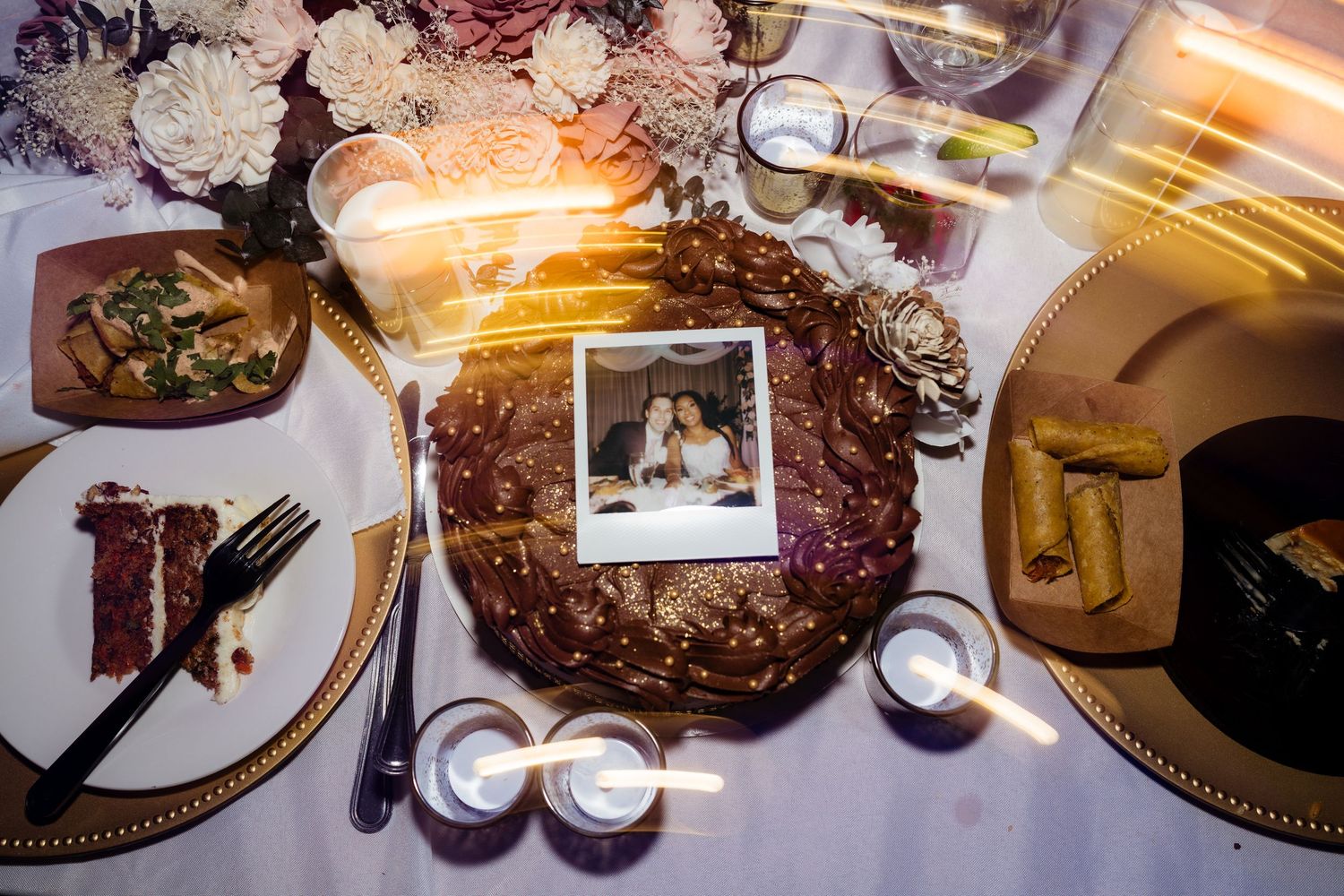 Elegant wedding reception table settings with ornate place settings and floral centerpieces illuminated by warm lighting.