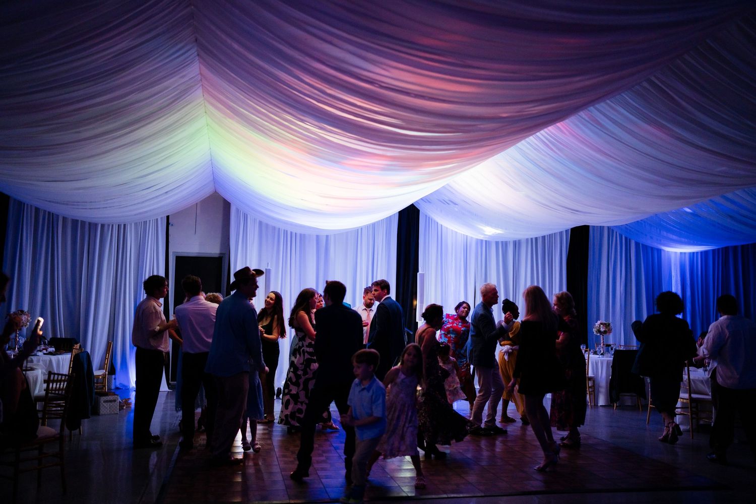 Wedding venue decorated with white fabric draping and dramatic blue lighting creating a romantic ambiance.