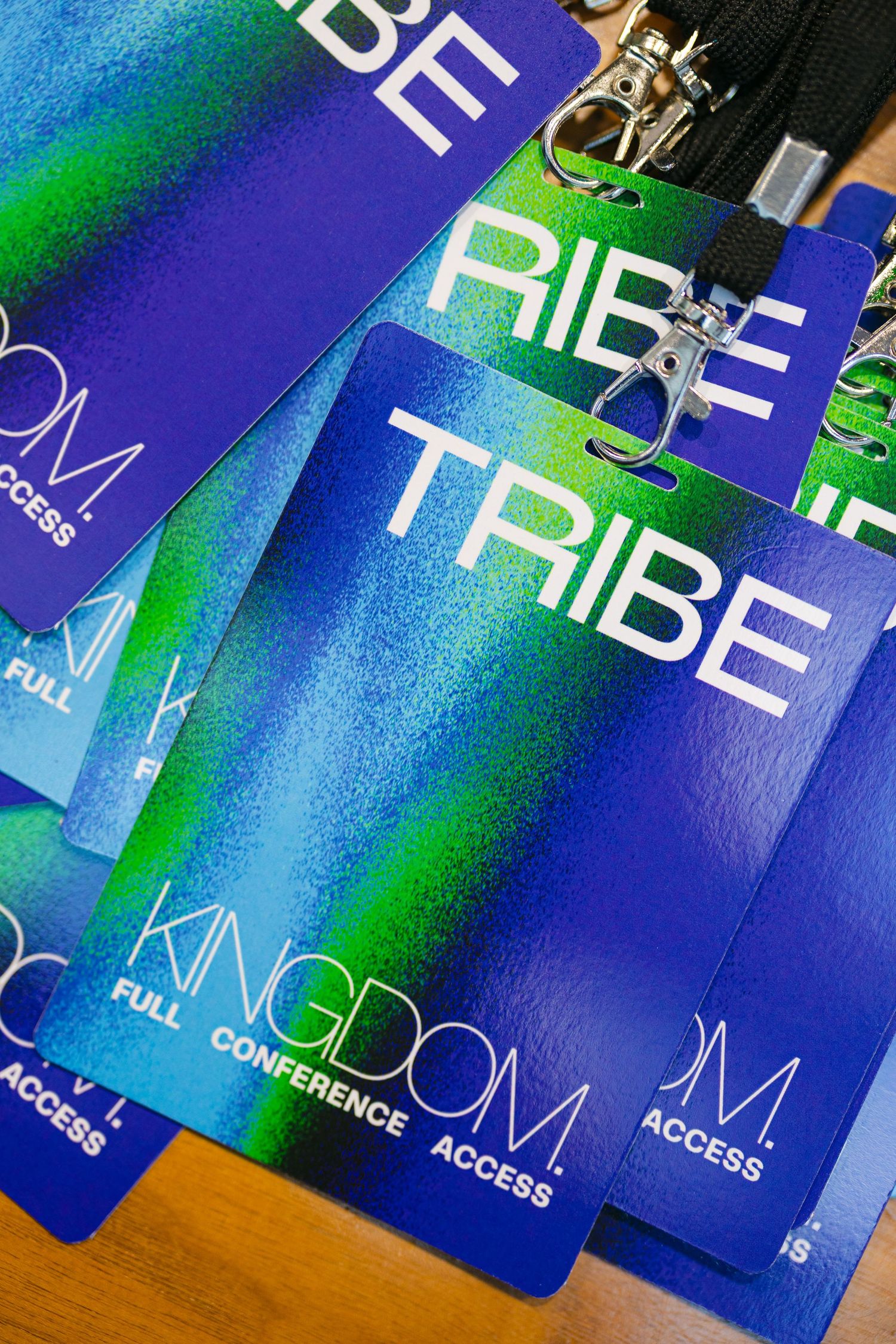 A row of blue event access passes or badges with text arranged in a diagonal line on a wooden surface.