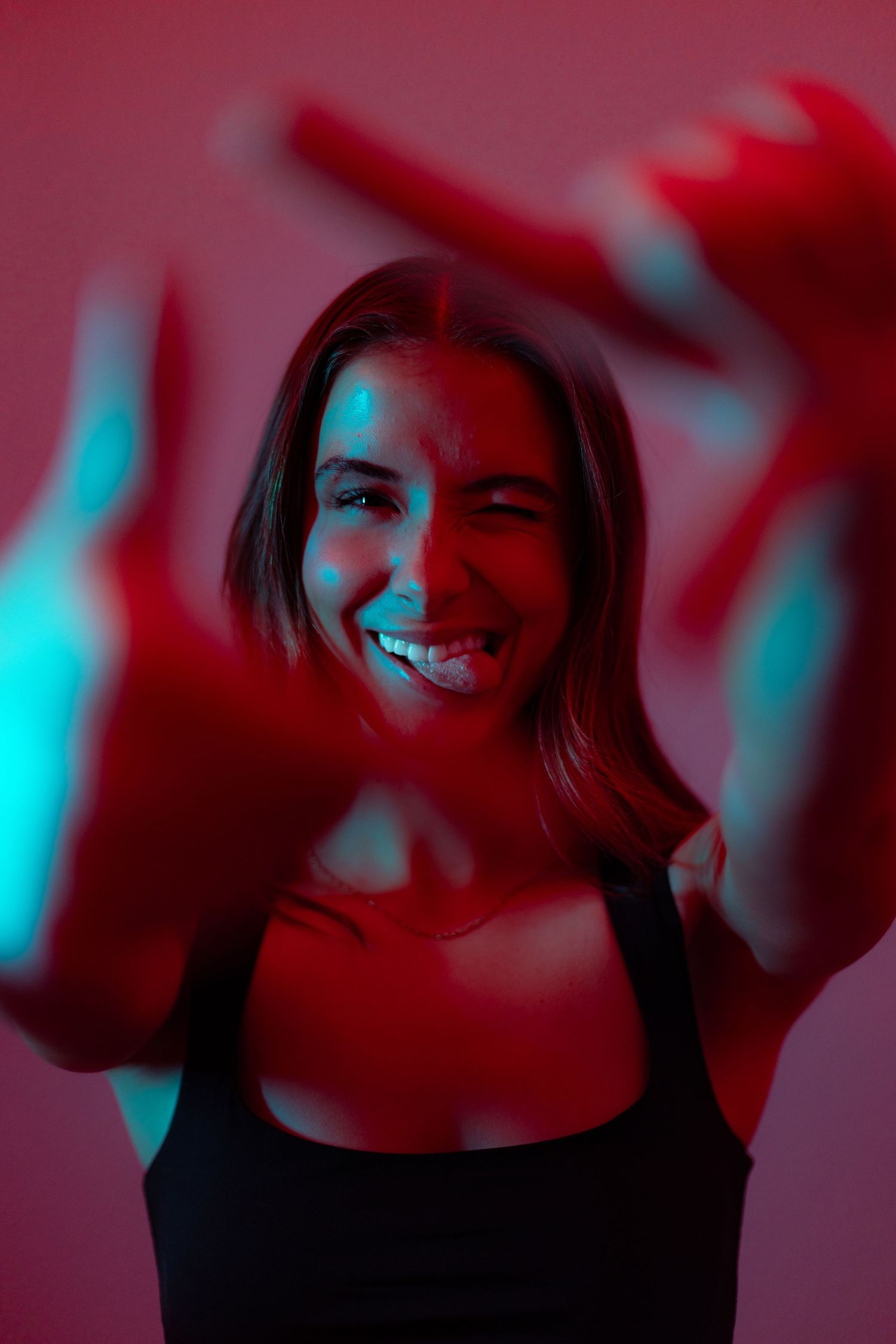 A sequence of portraits with red and blue lighting showing someone smiling and posing against a dark background.
