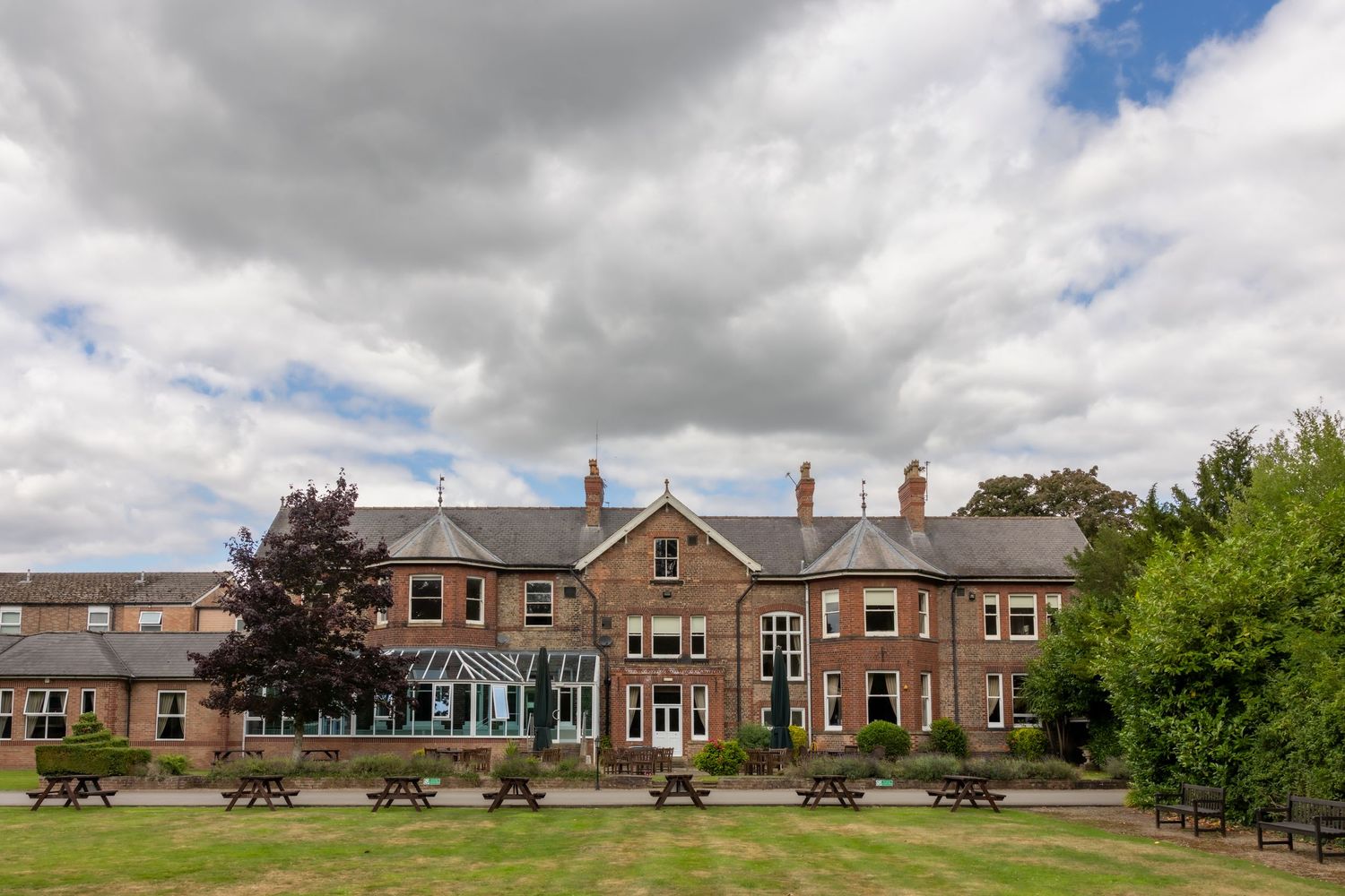 Panoramic view of modern brick residential homes with landscaped lawns and driveways under cloudy skies. Burn Hall Hotel, York Wedding