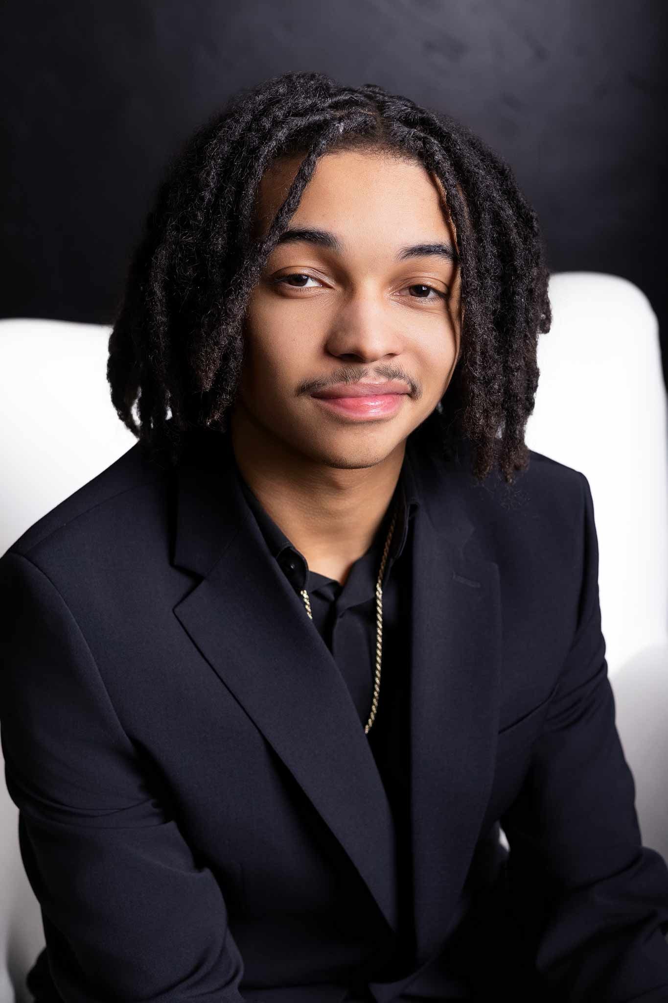 Professional headshot portrait in navy blazer against light background showing warm smile and natural hairstyle.