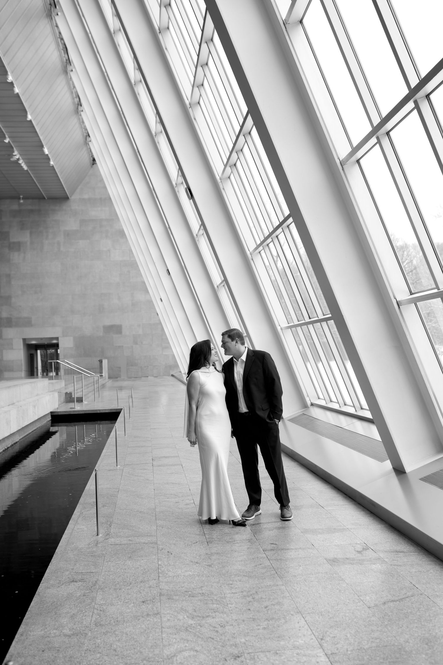 A black and white artistic sequence of a couple dancing in a modern architectural space with angled windows and natural light.