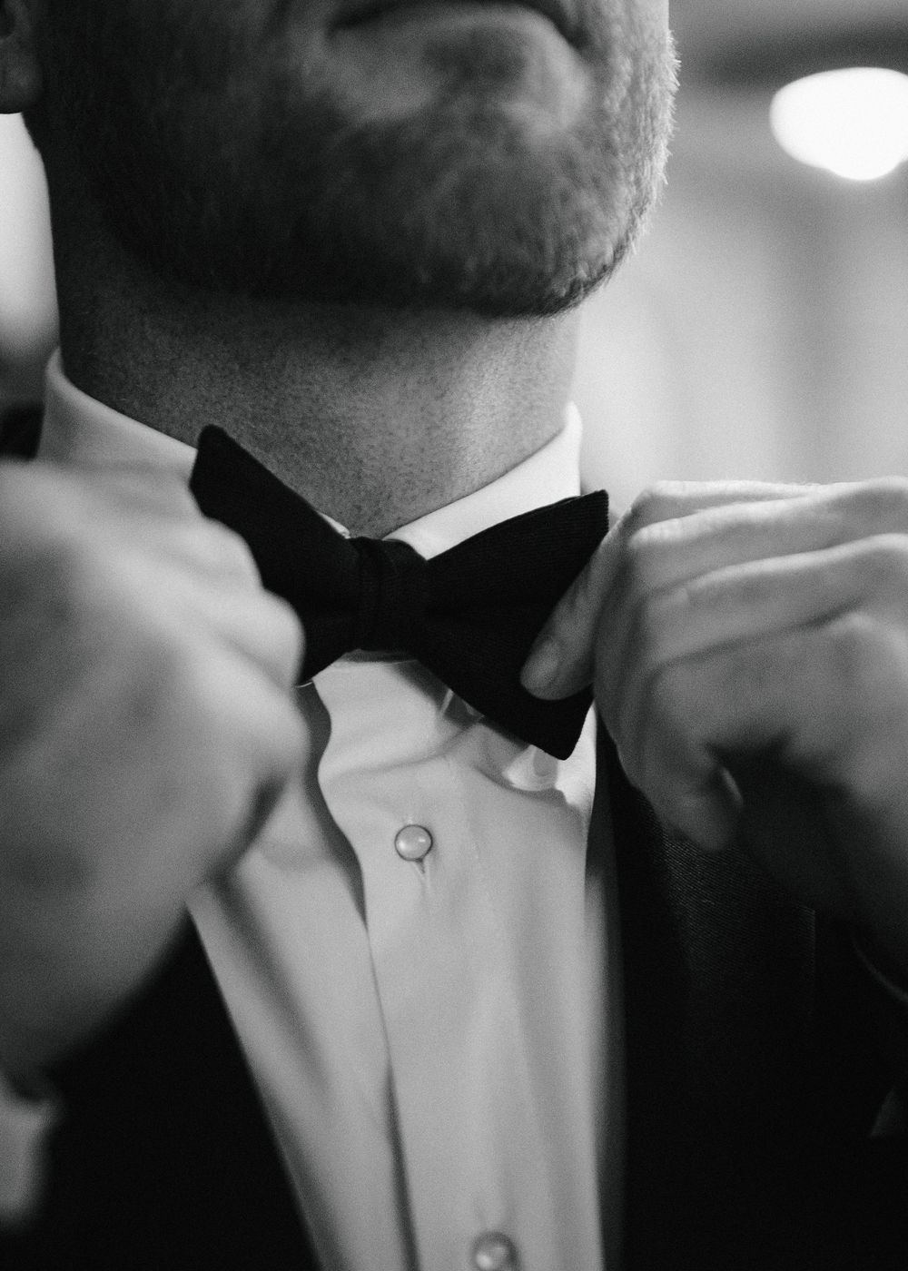 Close-up detail of a black bow tie and white dress shirt collar in black and white.