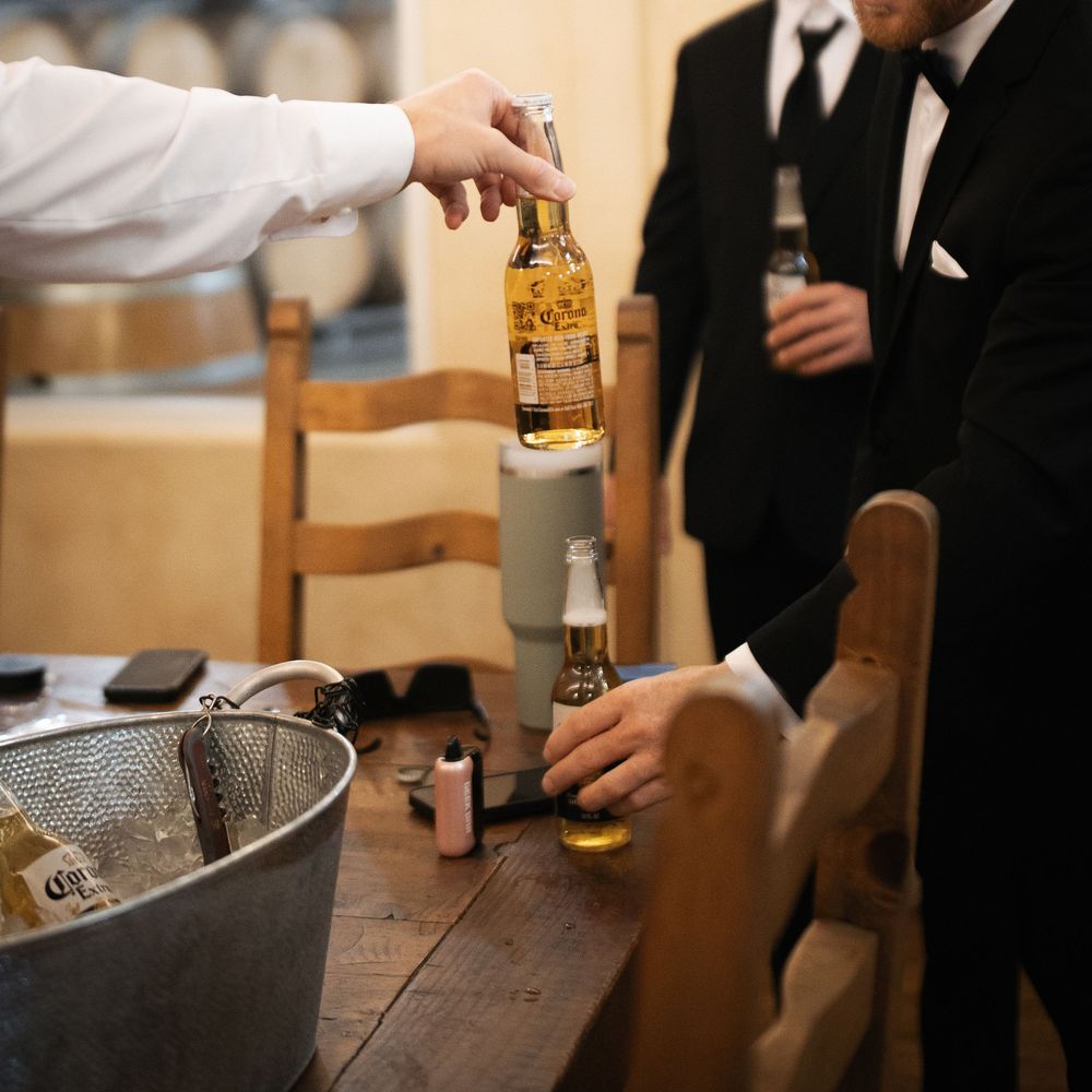 Wedding reception details showing beer bottles and bar setup in warm lighting.