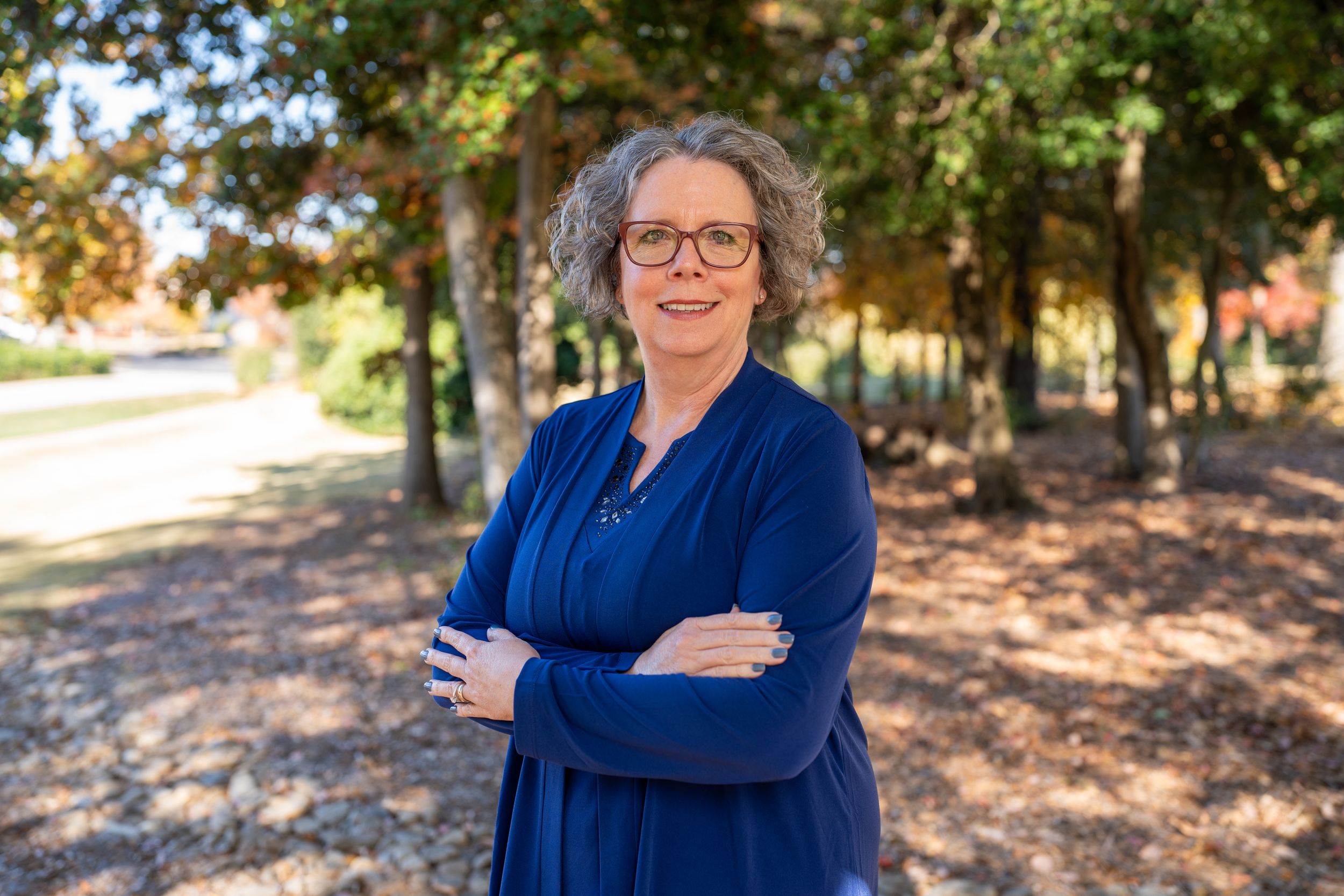 Professional outdoor portrait session in autumn featuring someone wearing a navy blue sweater against a backdrop of fall foliage.