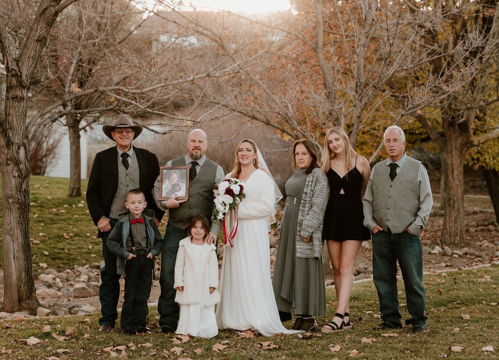 A group of people pose together outdoors in a fall setting with autumn trees and warm lighting.