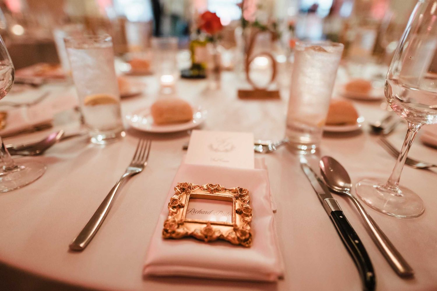 Close-up of wedding place setting with gold frame escort card at the Lenox Hotel Dome Room reception in Boston
